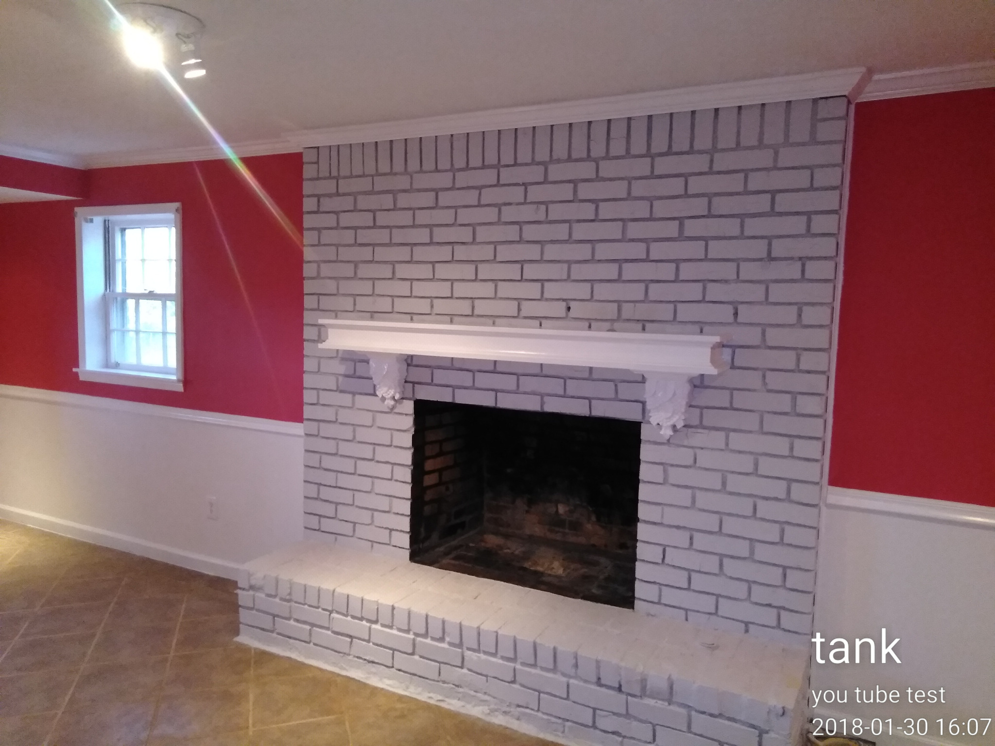 Red accent walls around a white brick fireplace