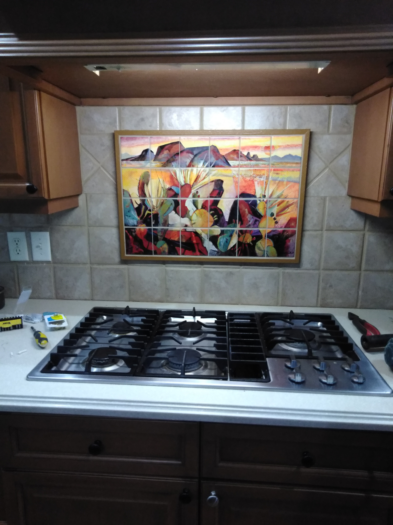 Custom tile artwork installed behind a kitchen cooktop